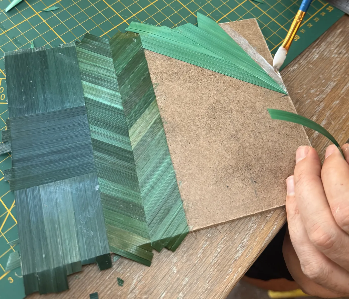 Pose des brins de paille teintée en vert sur un support en bois pendant un cours