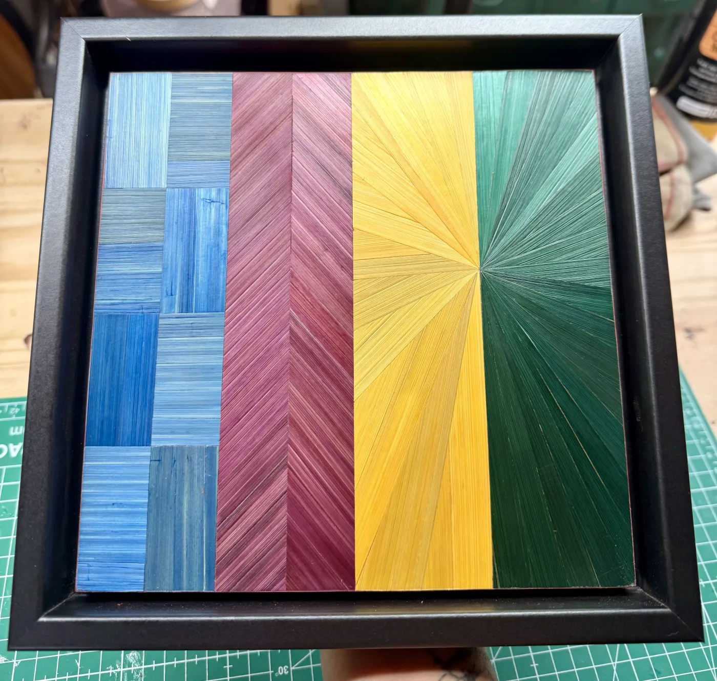 Panneau encadré réalisé en stage : damier bleu, chevrons prune, soleil jaune et vert