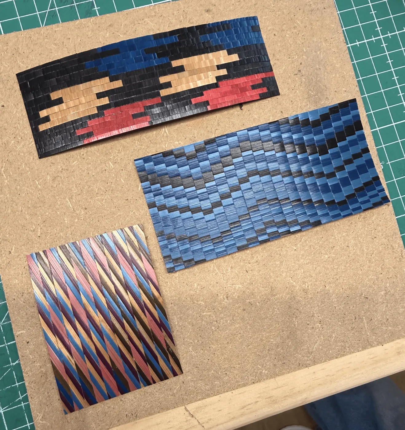 Trois échantillons de motifs en paille teintée bleu, noir et rouge réalisés en atelier